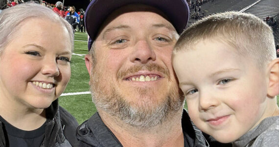 New Sequim athletic director/head football coach Ian Henley takes a family photo with his wife Jessica and son Rhys after a football game.