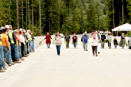 Photo by Dave Logan/for Olympic Peninsula News Group / Lower Elwha Klallam Tribal Chairwoman Francis Charles leads tribal members in a ceremony across the length of the new Elwha River bridge, which July 21. The tribal members dedicated the surface with cedar bows as members of the bridge crew watched from left.