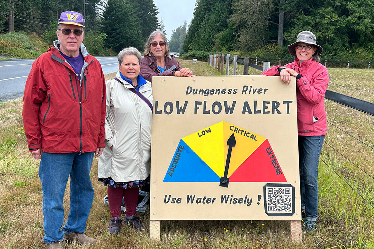 Sequim Gazette photo by Matthew Nash
David Brehm, Jeene Hobbs, Barbara VanderWerf and Ann Soule with the Clallam County League of Women Voters stand with a new sign that shows the level of water flow for the Dungeness River. While the river flow was considered “critical” on Aug. 23, that night, levels improved slightly to “low” flow. Soule said, “the ‘Critical’ zone was set for when irrigation managers potentially have to cut back their diversions and when biologists start planning ways to facilitate migration of salmon through shallow channels.” The sign is just west of Knutsen Farm Road on Old Olympic Highway. The group worked in conjunction with Tony Corrado, Mary Foster, Carrol Hull and Bonnie Bless-Boenish on information for the sign and website, with a QR code for up-to-date information. The sign will be updated weekly, organizers said.