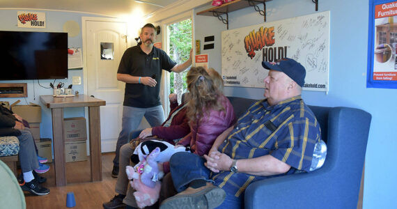 Tom Waertz of Ready America, left, runs an earthquake simulation in a shake trailer as participants, from left, Sequim EMT Lisa Law, CERT member Anne Koepp of Joyce and Jim Buck of the Joyce Emergency Planning and Preparation Group recover after being jolted by a 6.8-magnitude quake. (Keith Thorpe/Peninsula Daily News)