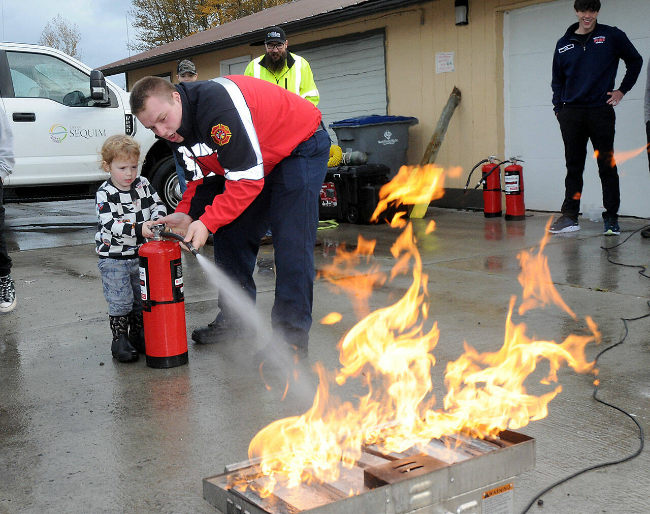 File photo by Keith Thorpe/Olympic Peninsula News Group
Beau Rossi, 2, of Sequim gets assistance from Clallam County Fire District 3 firefighter/paramedic Hayden Pyle with extinguishing an intentional propane fire during the Public Safety and Information Fair in 2023.