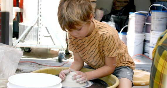 Eliott Carey, 5, shapes a mound of clay on a potter’s wheel on the patio of Peninsula College’s ceramics studio Saturday at its second Fall Spectacular. Playing with clay was one of many activities for children, families and adults at the event, which included tours of classrooms and introductions to courses and fields of study, Port Angeles Farmers Market booths, live music and an exhibition of art by college faculty. The event was a way for the people to learn about Peninsula College, meet faculty and staff and connect with community resources. Fall quarter at the college starts Sept. 26. (Paula Hunt/Peninsula Daily News)