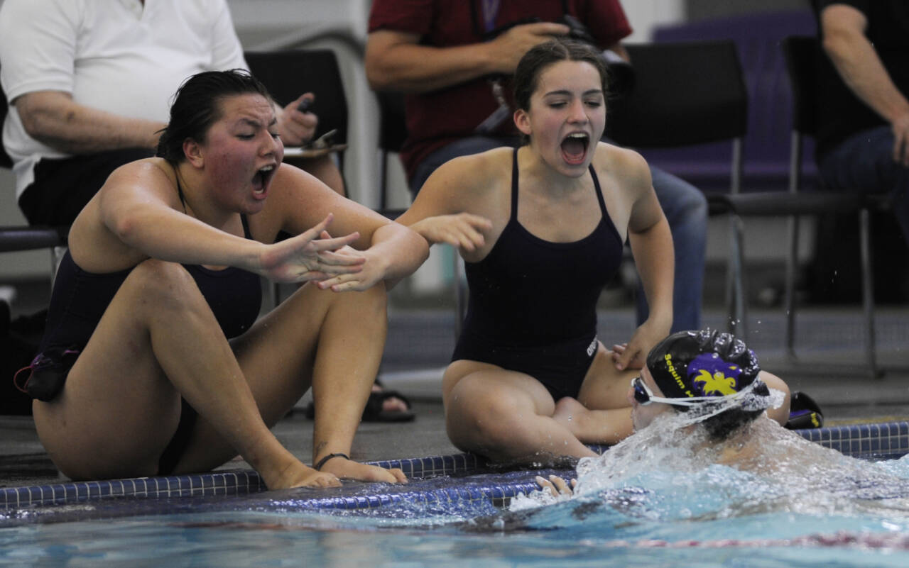 Sequim Gazette photo file by Michael Dashiell / Sequim’s Melia Nelson, left, and Ava Shinkle cheer on teammate Annie Ellefson in the 100 breaststroke as the Wolves take on Bremerton at home in a 2023 league meet.