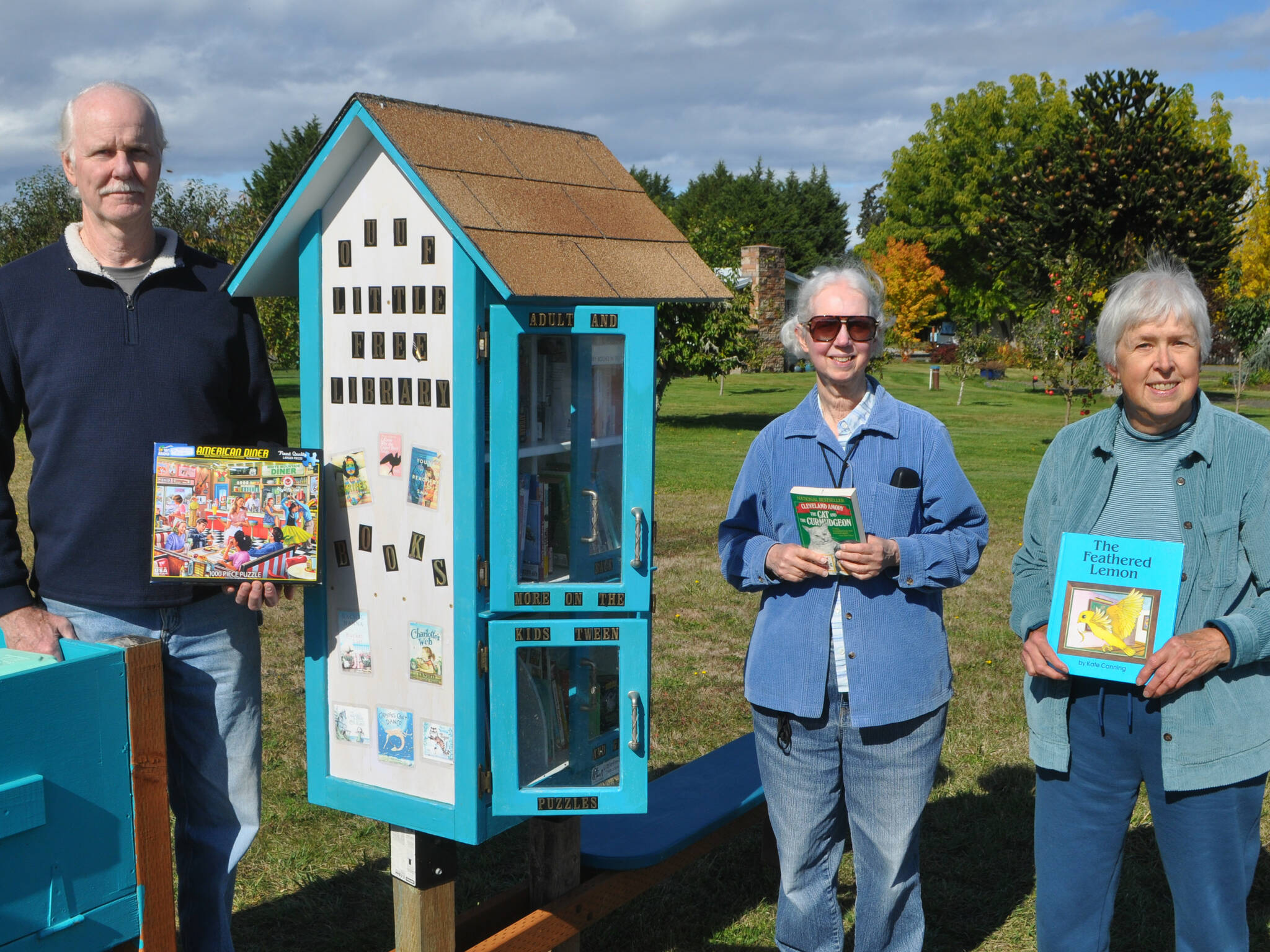 Sequim Gazette photo by Matthew Nash
Michael Clemens, Serena Mylchreest and Penny Burdick stand with the newly expanded and installed Little Free Library at the Olympic Unitarian Universalist Fellowship in Agnew. Mylchreest conceptualized the library in 2017, and this year Clemens built the newest iteration of the library and Burdick painted it. It’s available to anyone for free.