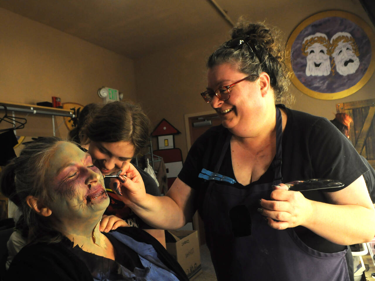 Sequim Gazette photo by Matthew Nash/ Makeup artists Sarana Vogel and Amy Henry zombify Rose Halverson into a veterinarian technician before a rehearsal of Olympic Theatre Arts’ “Night of the Living Dead.” Halverson, new to OTA, said she thought it’d be fun to act with her daughter Alivia in the show.