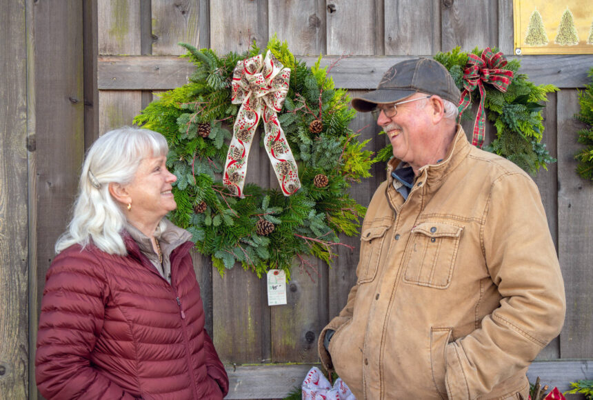 <p>Sequim Gazette photo by Emily Matthiessen</p>
                                <p>Outside the Christmas Barn at Lazy J Tree Farm, Ann and Steve Johnson smile at each other in front of wreaths Ann prepares with two other women for the Christmas season. Ann says they sell about 70 a year.</p>