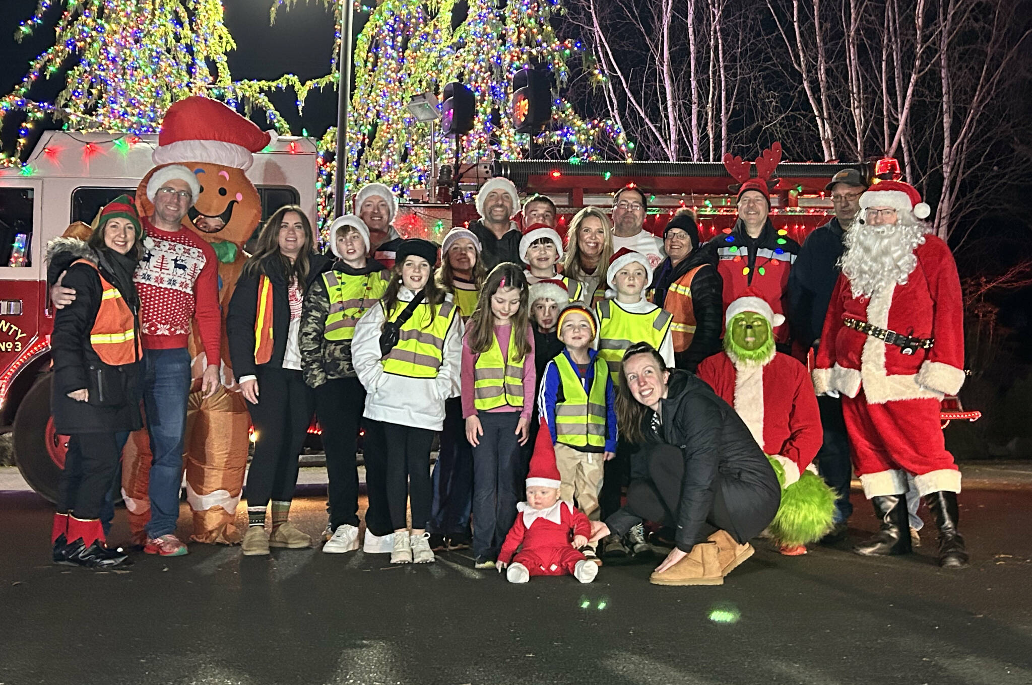 Sequim Gazette photo by Matthew Nash/ Santa’s Toy and Food Brigade takes a group photo on Dec. 5 at the Cedars at Dungeness with 8-month-old Hadley, dressed as the Elf on the Shelf, with her mom Ashleigh Clark.