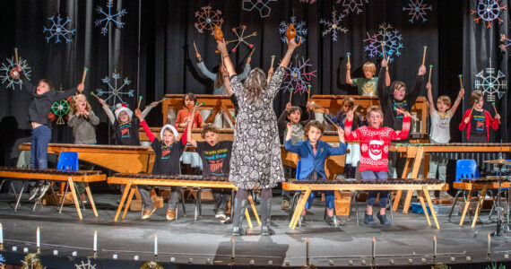 Sequim Gazette photo by Emily Matthiessen/ Five Acre School, a local non-profit elementary school, held their Winter Concert last Friday at Peninsula College under the direction of music and art teacher Rosie Sharpe. The children made the giant decorative wooden snowflakes.