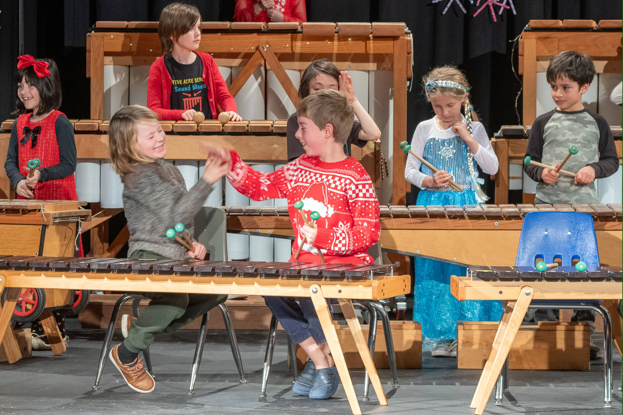 Sequim Gazette photo by Emily Matthiessen/ Five Acre students exchange a high-five on the successful completion of their marimba songs during their Winter Concert held at Peninsula College last Friday. The non-profit elementary school is celebrating their 30th anniversary and is in the midst of a fundraiser for their tuition assistance program.