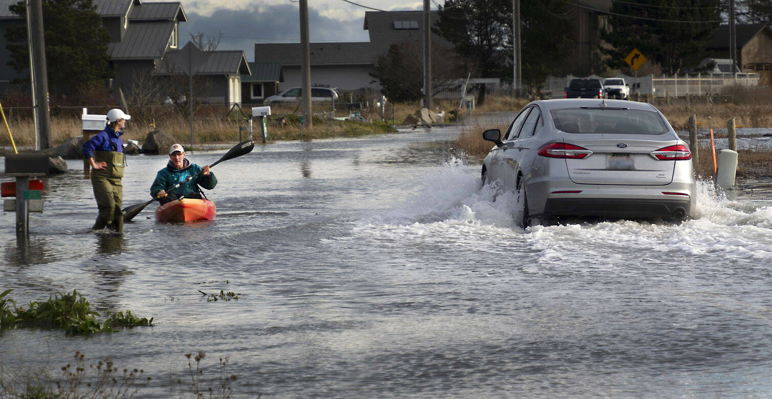 Photo courtesy Cath Hickey
A car passes through high water on 3 Crabs Road on Dec. 14 as neighbors make their way down the street by foot and boat.