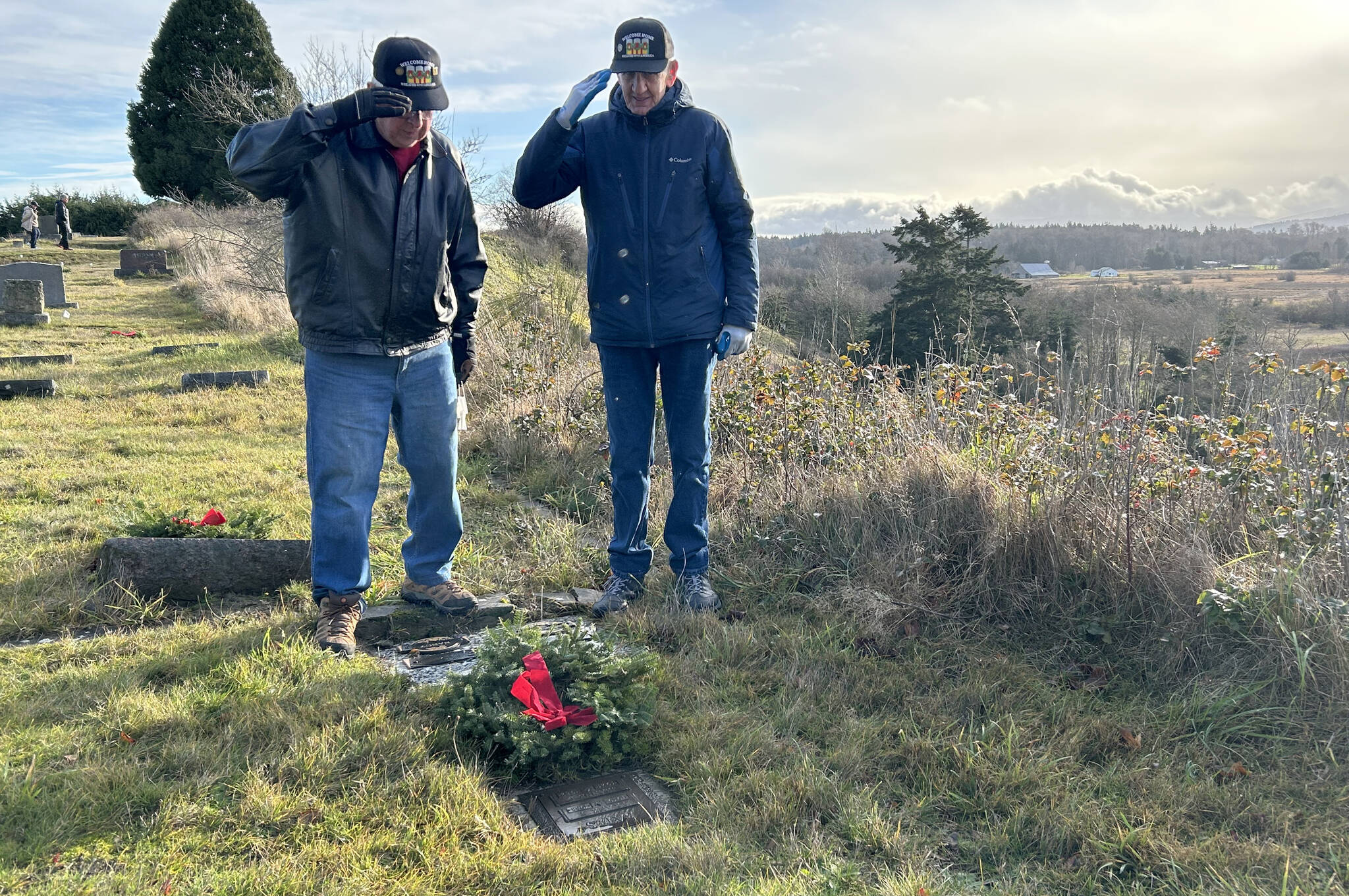 Vietnam veterans Randy Skoglund, a U.S. Navy air traffic controller, and Jim Fosse, a U.S. Army LRRP, salute on Dec. 14 a grave after placing a balsam wreath as part of National Wreaths Across America Day.