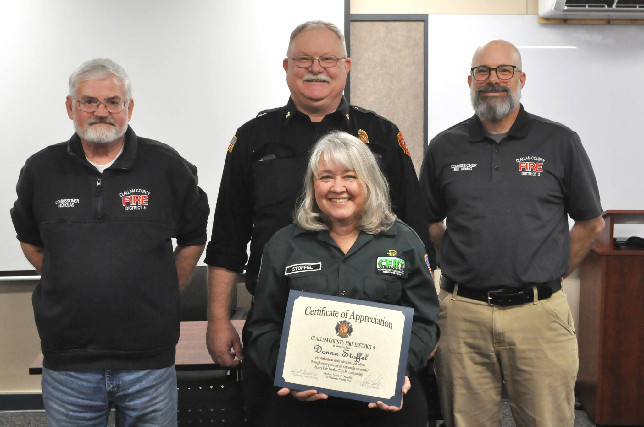 Sequim Gazette photo by Matthew Nash
Donna Stoffel, organizer of the second Sequim Public Safety Fair, is honored with a certificate of appreciation on Dec. 17 from, top left, Clallam County Fire District 3 commissioner Jeff Nicholas, fire chief Justin Grider and commissioner Bill Miano.