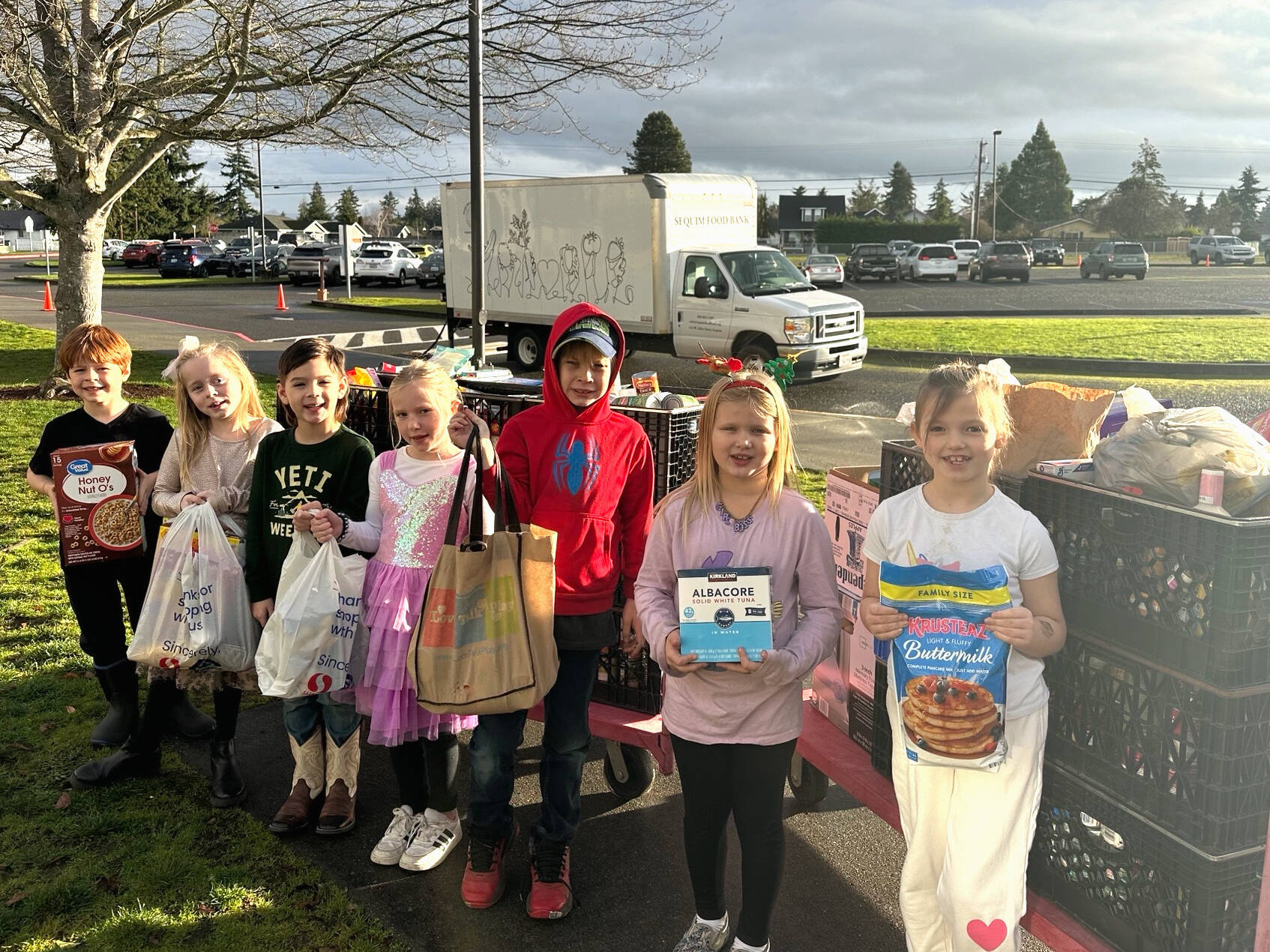 Photo courtesy Darcy Lamb 
Greywolf Elementary first graders in Rachel Peck and Cricket Hagan’s class, from left, Lucas Kroh, Dakota Joslyn-Crass, Oliver Vargas, Ruby Miller, Logan Tinkham, Autumn Glen, and Freya Welch stand with donations to Sequim Food Bank for 12 Days of Giving. School leaders said each class won an extra recess at least once for donating the most items each day.