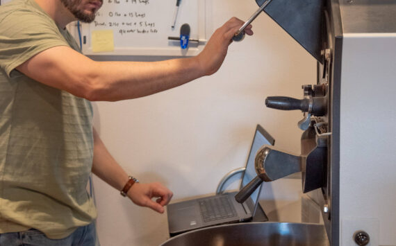 Sequim Gazette photo by Emily Matthiessen/ Home from Seattle for the weekend, cancer patient Rod Dirks calibrates the roasting machine at Essence Coffee Roasters, which he owns with his wife Megan.