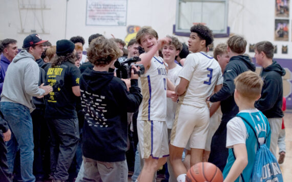 Sequim Gazette photo by Emily Matthiessen/Sequim students storm the court and celebreate with Ethan Melnick (0) and Solomon Sheppard (3) after the Wolves beat Bremerton 66-61 on Monday night to earn a share of the Olympic League boys basketball championship. Sequim and Bremerton will play in Poulsbo Wednesday in a rubber match to determine playoff seeding.